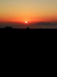 Scenic view of silhouette landscape against orange sky