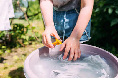 Little preschool girl helps with laundry. child washes clothes in garden