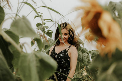 Portrait of young woman standing at sunflower farm