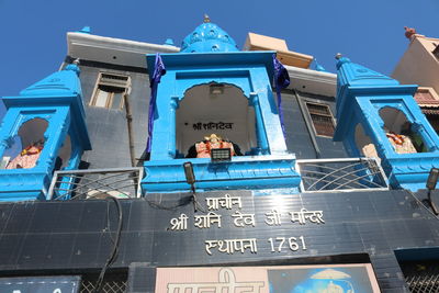 Low angle view of text on building against clear blue sky