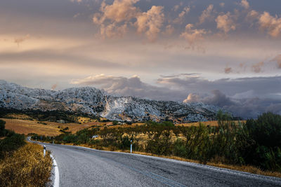 Empty road by mountains against sky