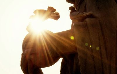 Low angle view of sun shining through statue