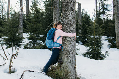 A beautiful girl hugs a tree trunk in the forest with a smile. the concept of love for nature 