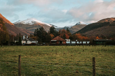 Houses on field by mountains against sky