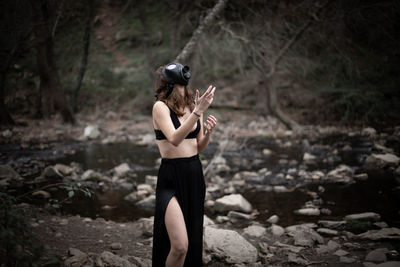 Side view of sensuous woman wearing gas mask while standing in forest