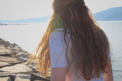 Rear view of woman at beach against clear sky