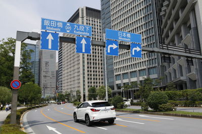 Cars on road in city against blue sky