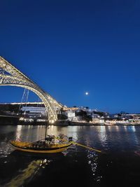 Illuminated bridge over river against sky at night