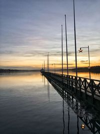 Pier on lake against sky during sunset