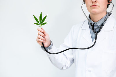 Midsection of woman holding plant against white background