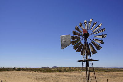 Traditional windmill on field against clear blue sky