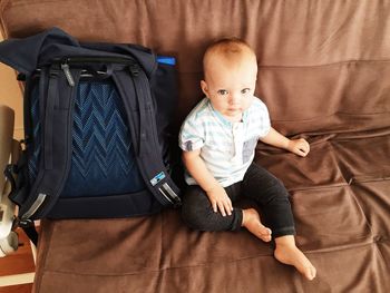 High angle portrait of baby boy sitting on sofa