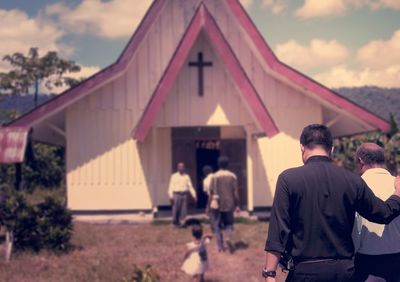 Rear view of son with father walking against church