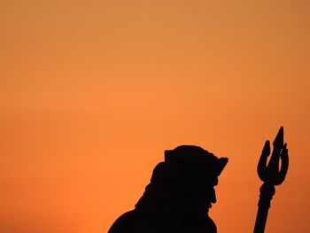 Low angle view of silhouette hand against orange sky