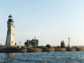 Lighthouse by sea against sky