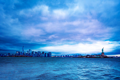 City at waterfront against cloudy sky