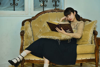 Young woman using laptop while sitting on chair at home