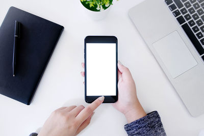 Low section of person using mobile phone on table