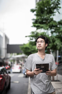 Young man using mobile phone while standing on road