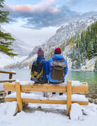 Rear view of man sitting on snow covered landscape