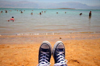 Low section of person wearing shoes at beach