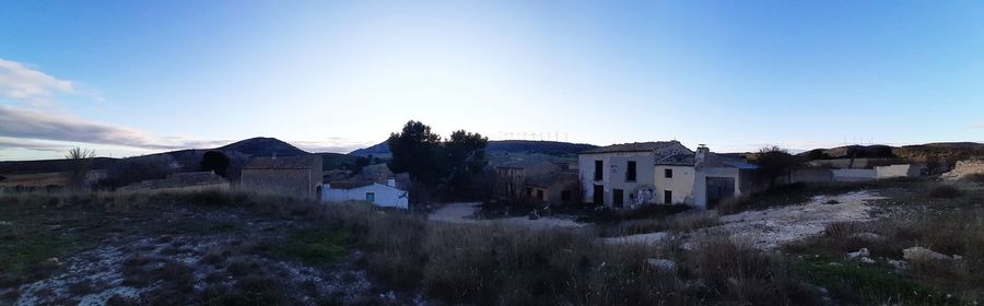 Houses on field by buildings against clear blue sky