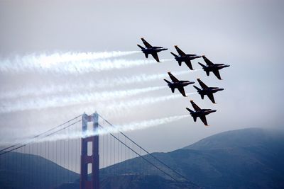 Blue angels flying against golden gate bridge