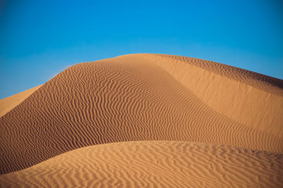 Scenic view of desert against clear blue sky