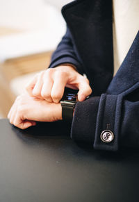 Midsection of person using smart watch on table