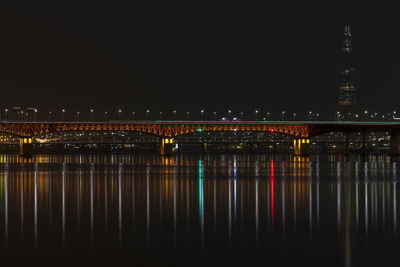 Bridge illuminated in river at night
