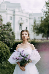 A beautiful delicate elegant young woman bride in a wedding dress walks alone in a spring park