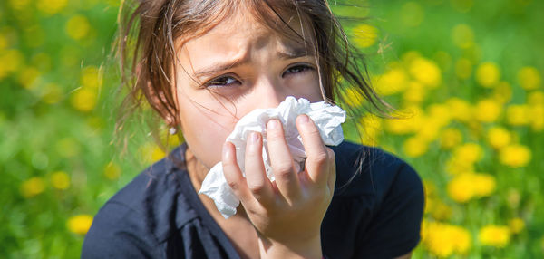 Portrait of girl blowing nose with tissue paper