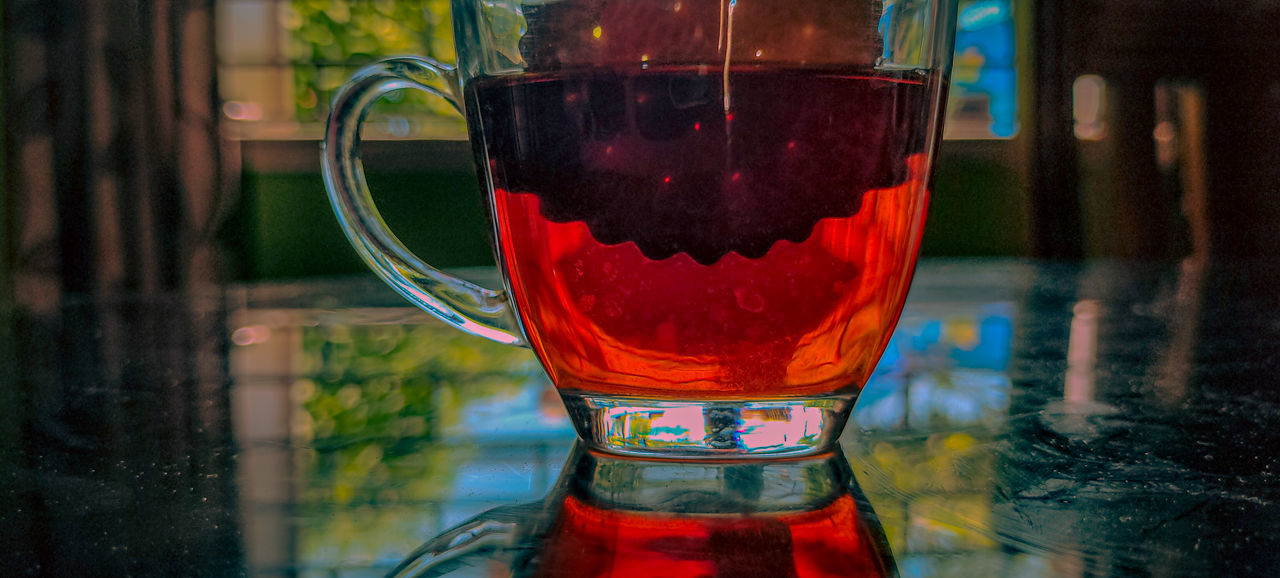red, drink, glass, food and drink, refreshment, alcoholic beverage, soft drink, household equipment, drinking glass, close-up, focus on foreground, no people, table, indoors, reflection, freshness, water, transparent, still life, cup, alcohol