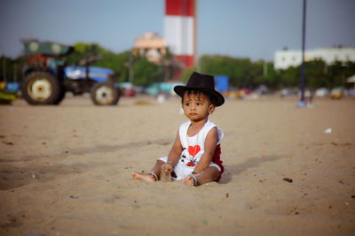 Portrait of young woman sitting on sand at beach