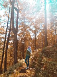 Woman standing by trees in forest