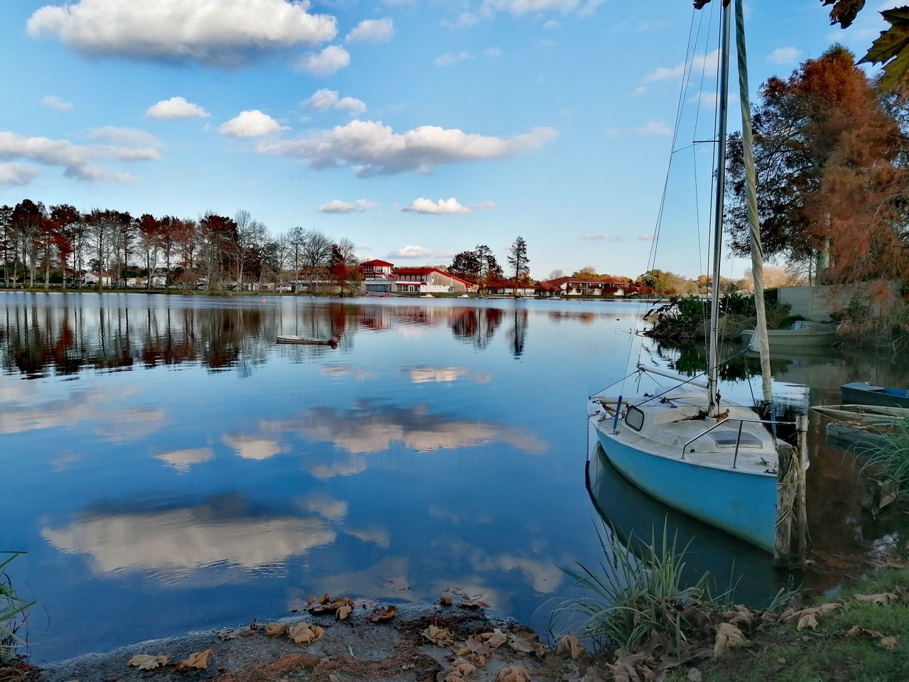 water, reflection, sky, nautical vessel, nature, cloud, river, shore, transportation, moored, tranquility, tree, no people, mode of transportation, beauty in nature, plant, body of water, scenics - nature, vehicle, tranquil scene, boat, day, dock, beach, outdoors, travel destinations, waterway, travel, morning, land, architecture, bay, ship, landscape, idyllic, coast, non-urban scene, harbor, blue, environment