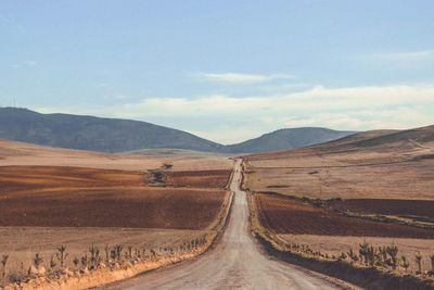 Road leading towards mountains against sky