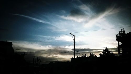 Low angle view of electricity pylon against cloudy sky