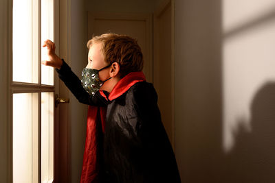 Side view of woman standing against window at home