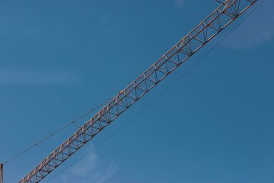 Low angle view of crane against clear blue sky