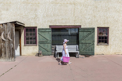 Side view of woman walking on footpath against building