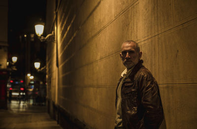 Adult man on street against brick wall with light of street lamp at night. shot in madrid, spain