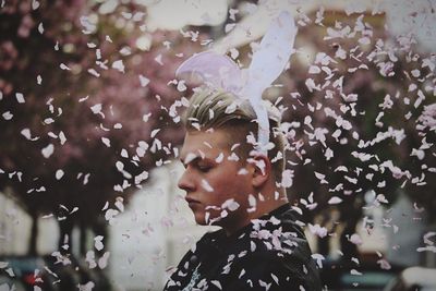 Side view of man wearing costume rabbit ears amidst pink confetti