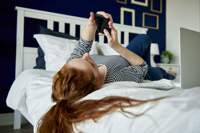 Midsection of woman lying down on bed at home