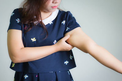 Midsection of woman touching hand against white background