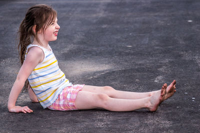 Full length of girl sitting on road