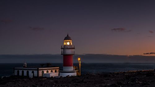 Lighthouse amidst sea and buildings against sky