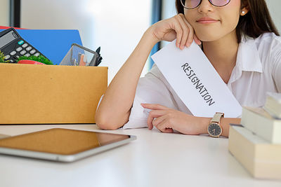 Midsection of woman packing box on desk at office after resignation