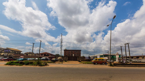 Cars on road by buildings against sky