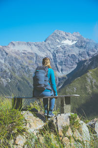 Rear view of woman looking at mountains while sitting on bench